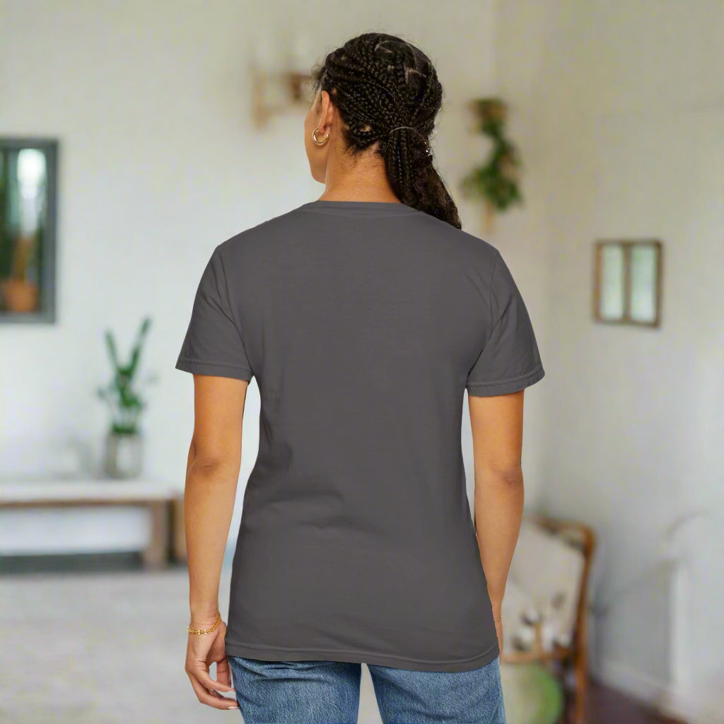 A woman standing and turned around to display the back of the gray 'I See Good People' unisex t-shirt. The garment-dyed fabric and relaxed fit are highlighted, showcasing the shirt's comfortable design and casual style.