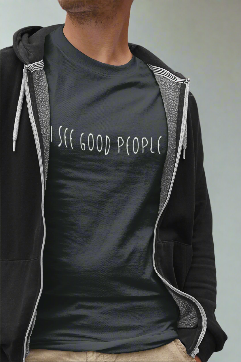 Mockup of a young man wearing a black 'I See Good People' unisex t-shirt paired with a casual hoodie. The t-shirt features a minimalist white text design and promotes positivity in a relaxed, modern style.