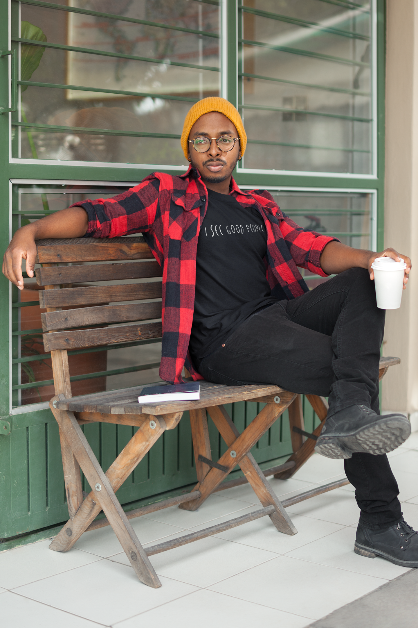 A mockup of a man wearing a black 'I See Good People' t-shirt styled with casual fall clothing. The minimalist white text design on the garment-dyed fabric complements the cozy seasonal outfit, showcasing the t-shirt's relaxed fit and versatility for everyday wear.